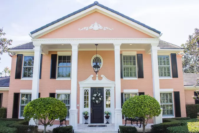 Black louvered Colonial Shutters on a salmon-colored colonial home