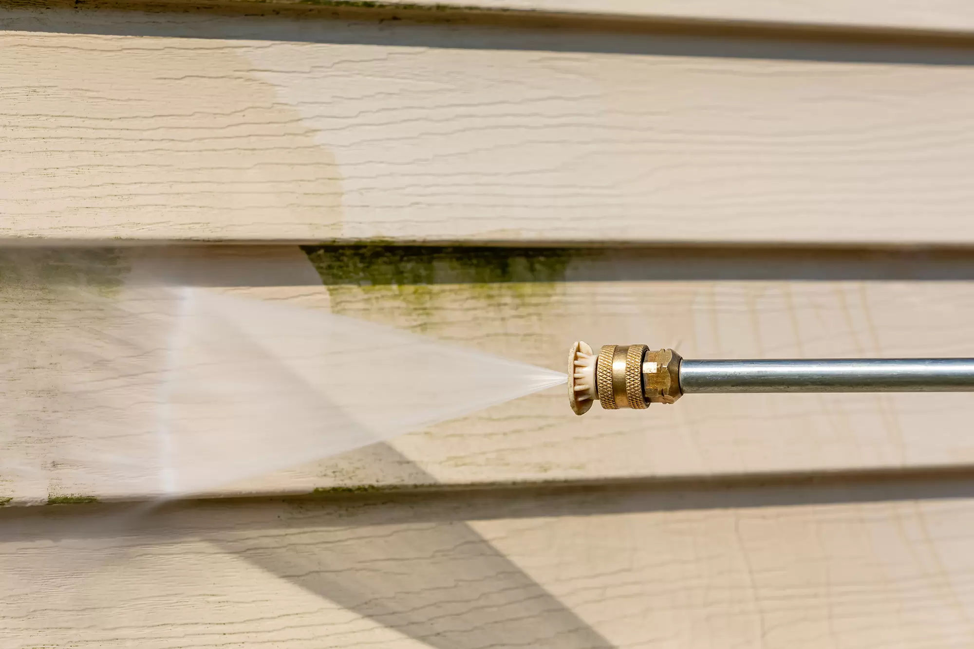 Pressure washing green mold from house siding.