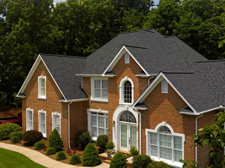 Brick exterior of a two-story home with black shingle roofing.