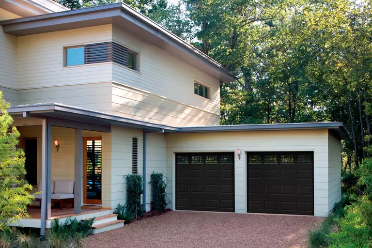 Contemporary home with black raised panel garage doors.