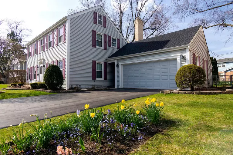 Front yard of a home with a driveway and a light gray raised-panel garage door.