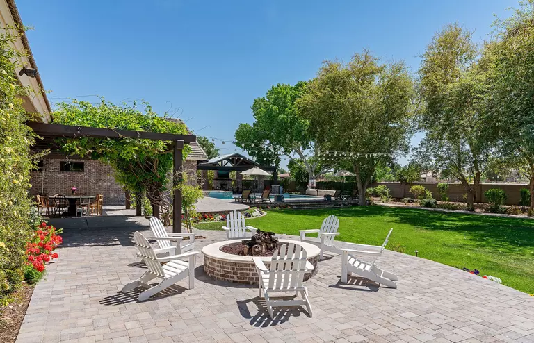 A group of outdoor chairs arranged in a circle around a fire pit. The area looks ideal for conversations around the fire with friends.