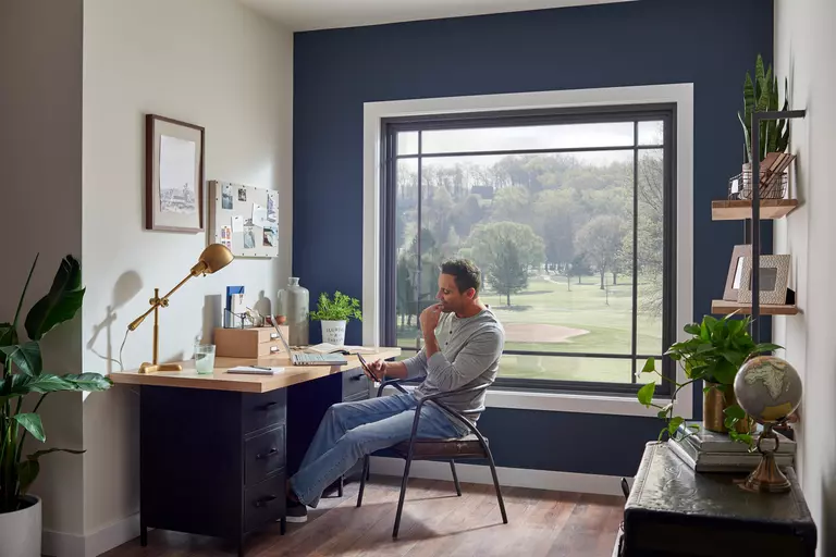 Big window in an office space with a man using his phone.