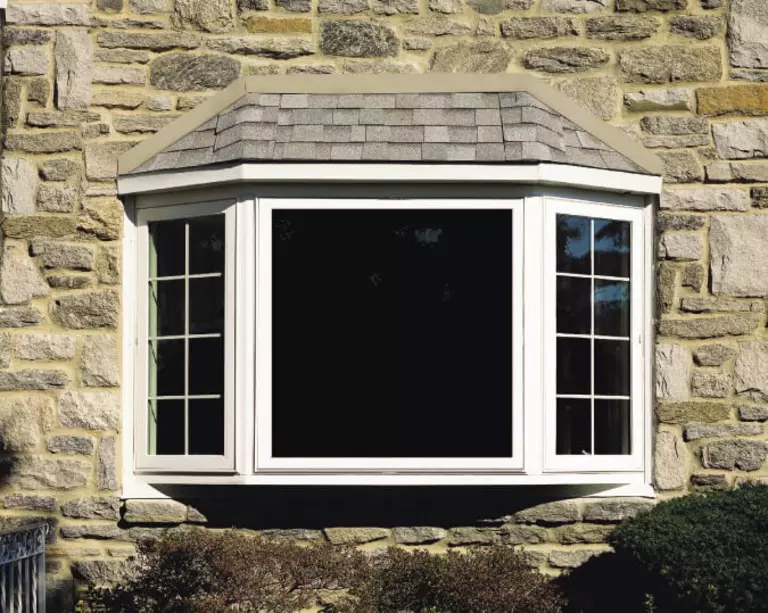An exterior view of a bay window on a stone house. 