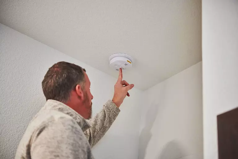 Man checking the smoke detector on the ceiling of his home.