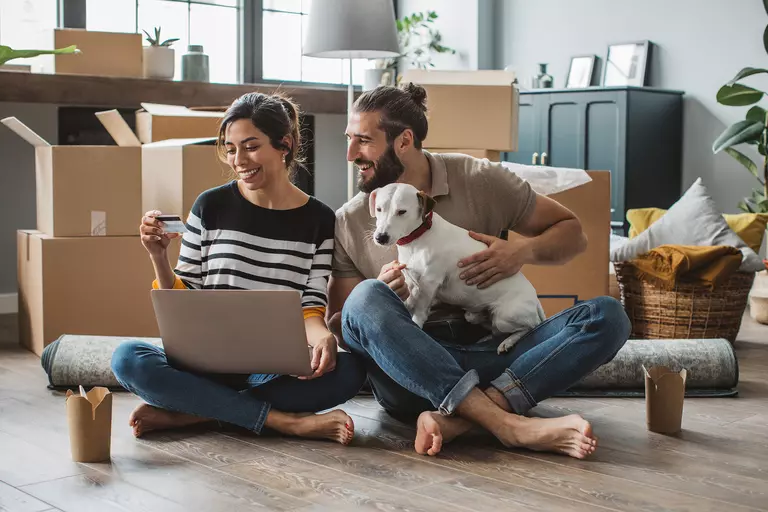 Man with a family dog and a woman with a laptop and a credit card.