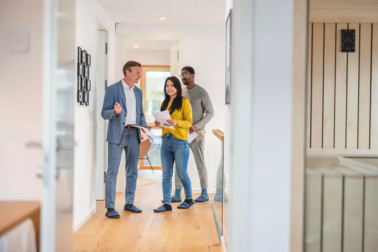 Man in a business suit showing the interior of a home to a couple.