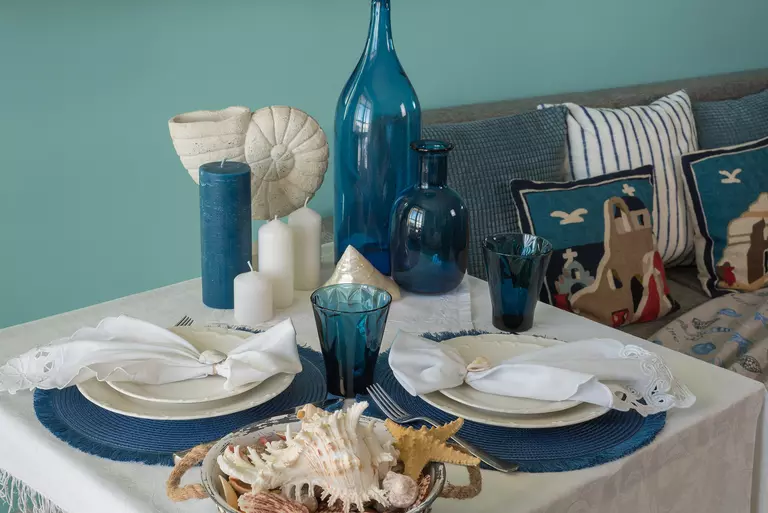 An ocean-themed dishware set laid out on the dinner table in a turquoise, beach-themed dining room.