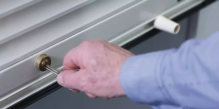 A person inserting a key into a window keyed lock