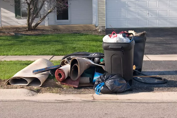 Trash on the side of a road in front of a house