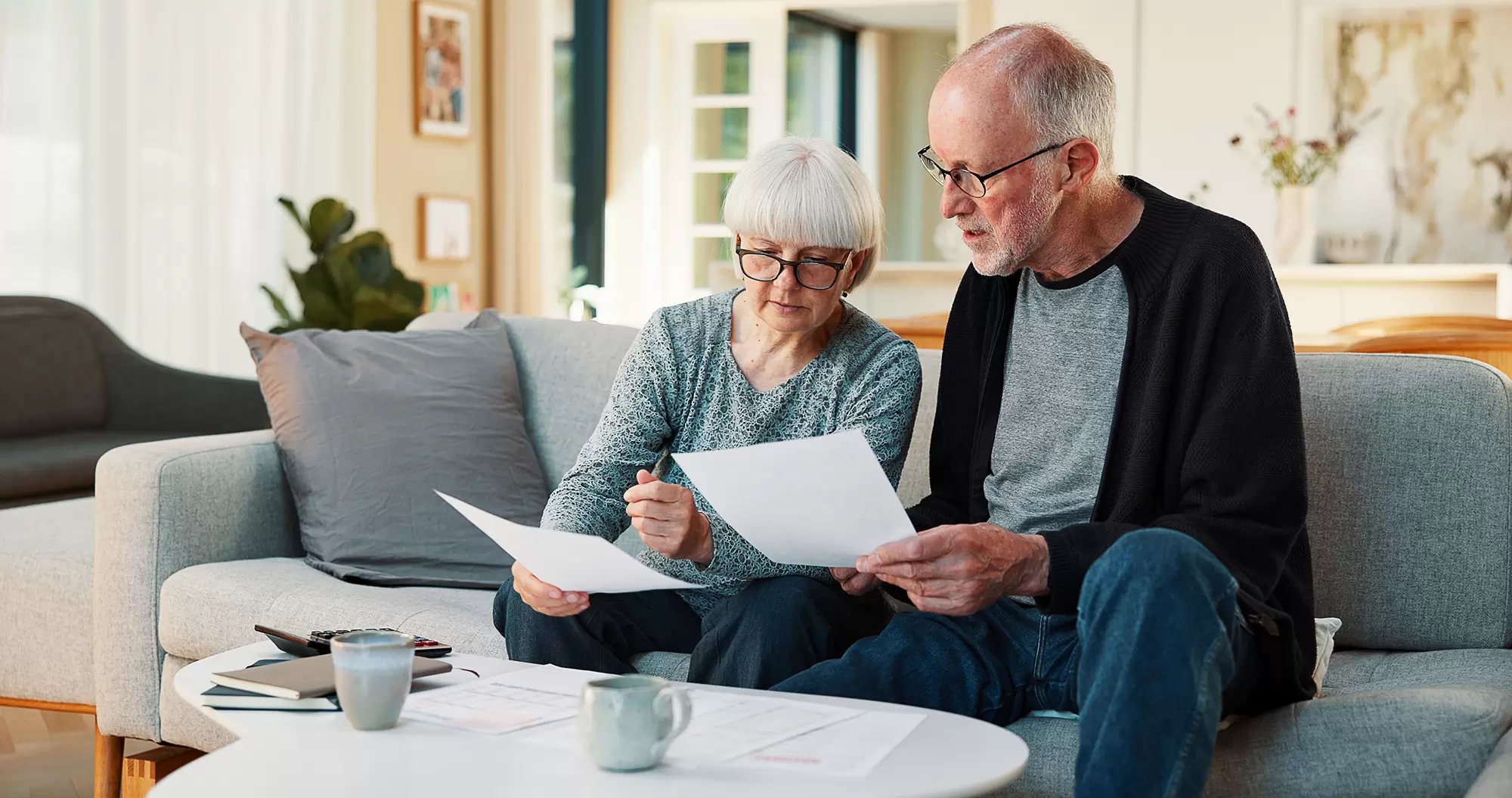 Man and woman on a couch reviewing documents together.