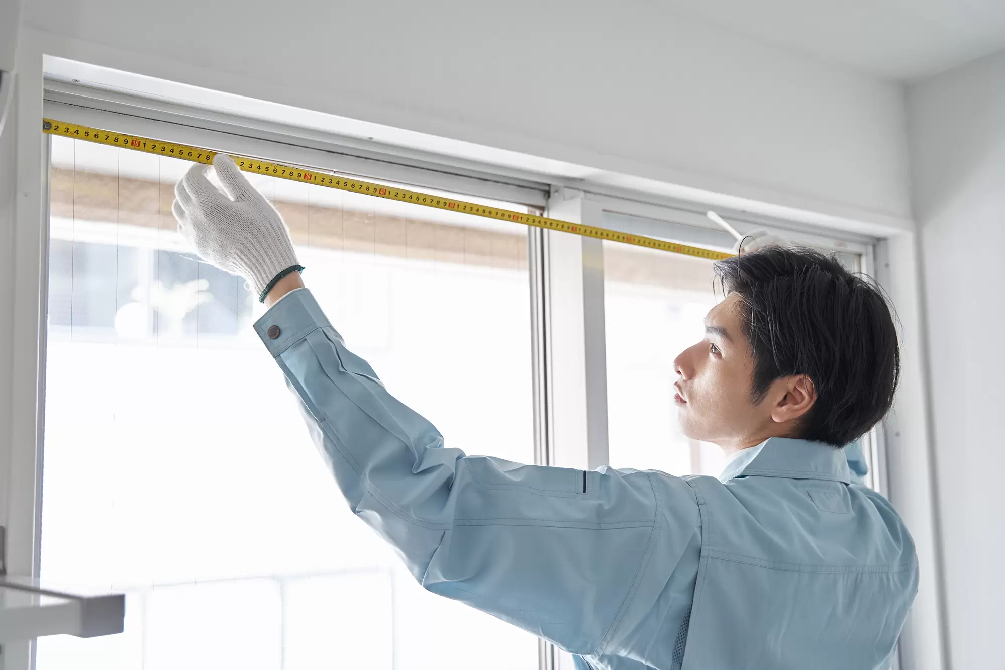 Worker measuring the size of a window frame.
