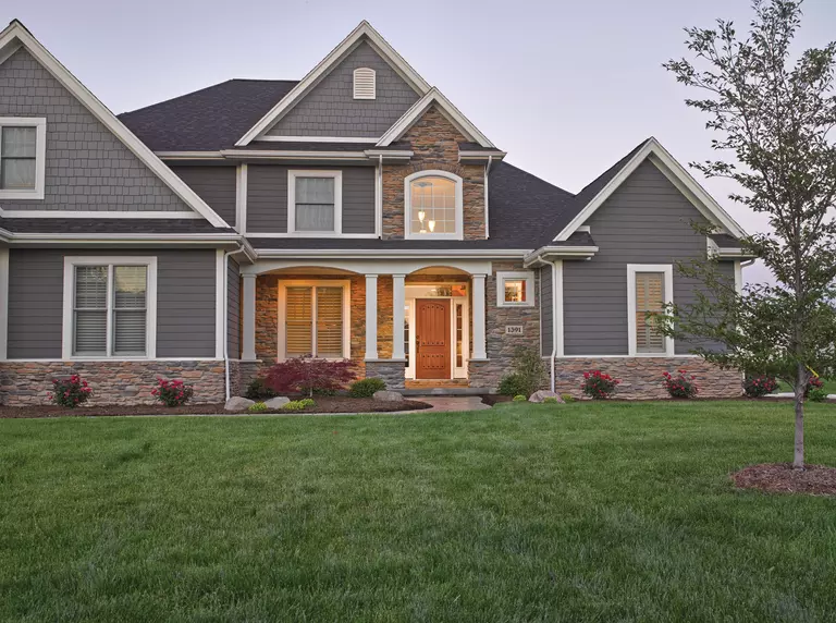 A siding and stone two-story home on a large piece of land with large energy-efficient windows.
