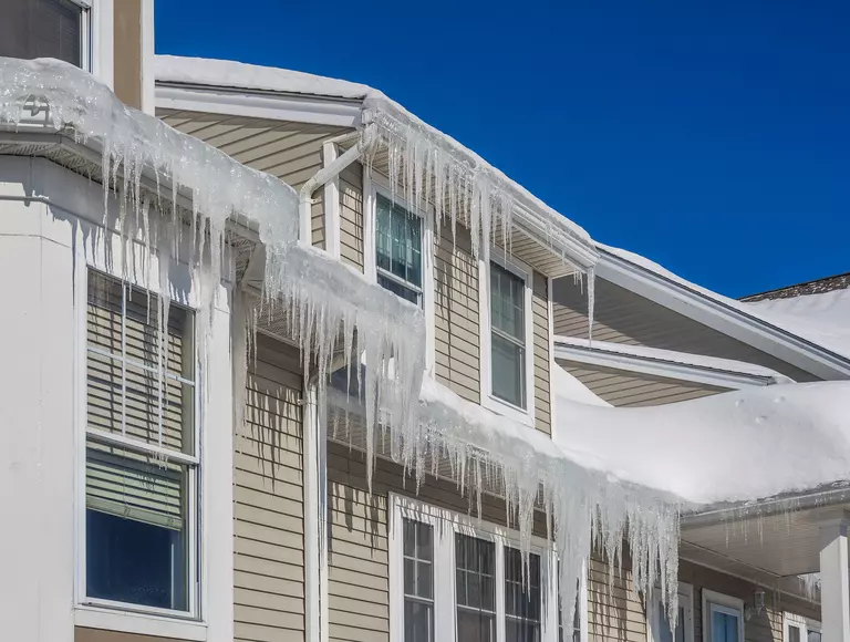 The upper exterior of a home with large ice dams in the gutters.