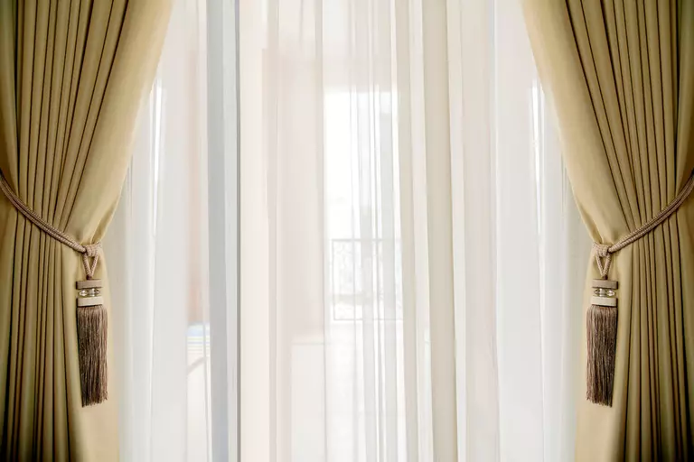 Gold-colored velvet drapes and white curtains with plenty of natural light.