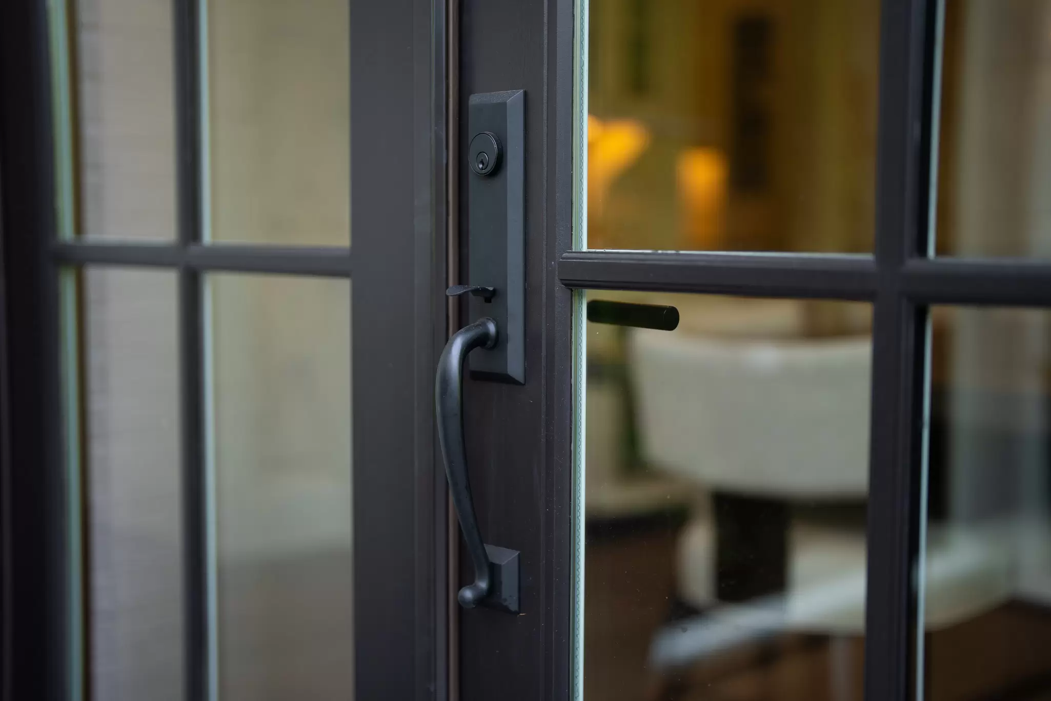 Close-up of the black handle and lock hardware on a hinged French patio door.