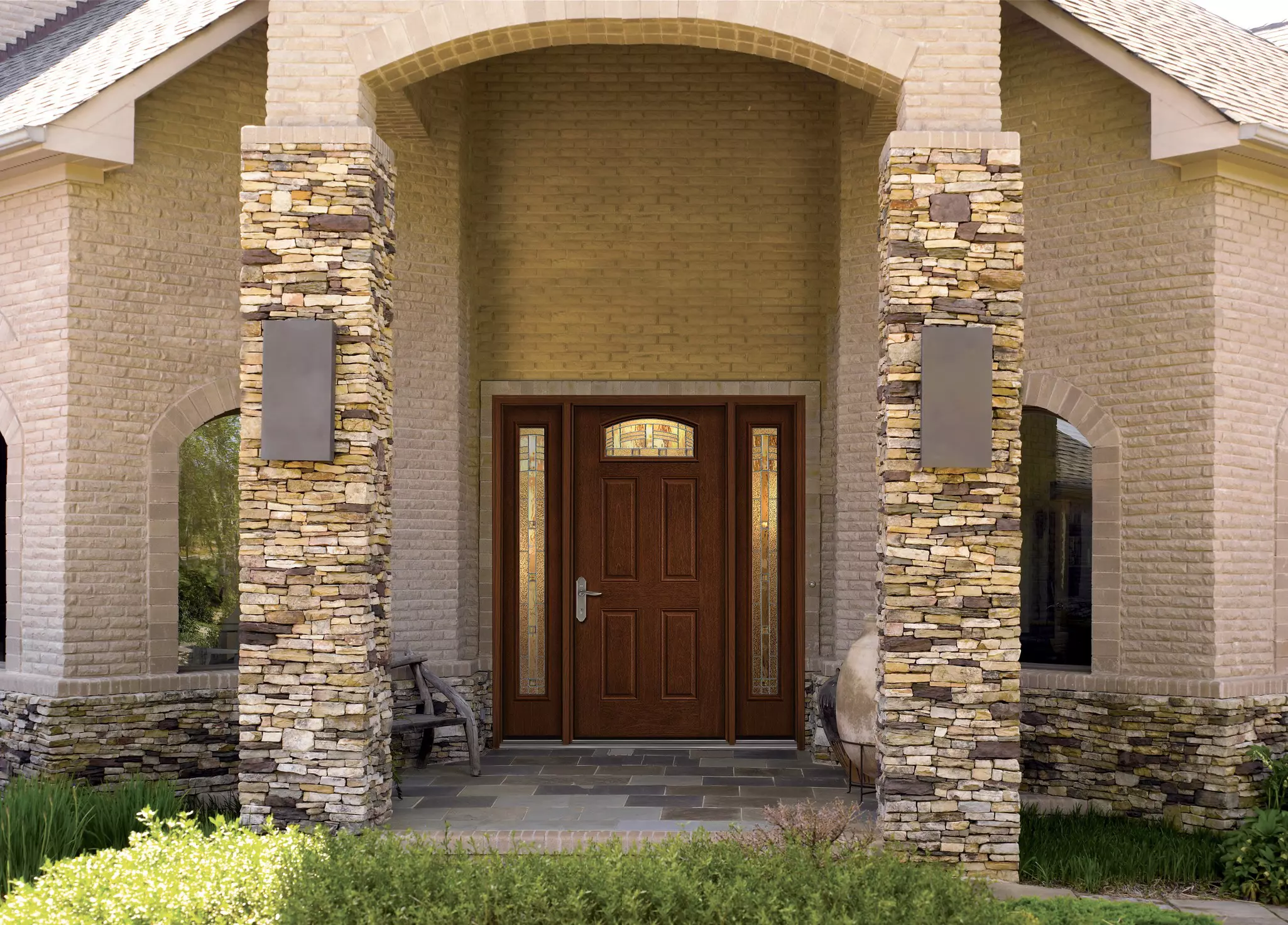Woodgrain fiberglass entry door with decorative glass and a transom window.