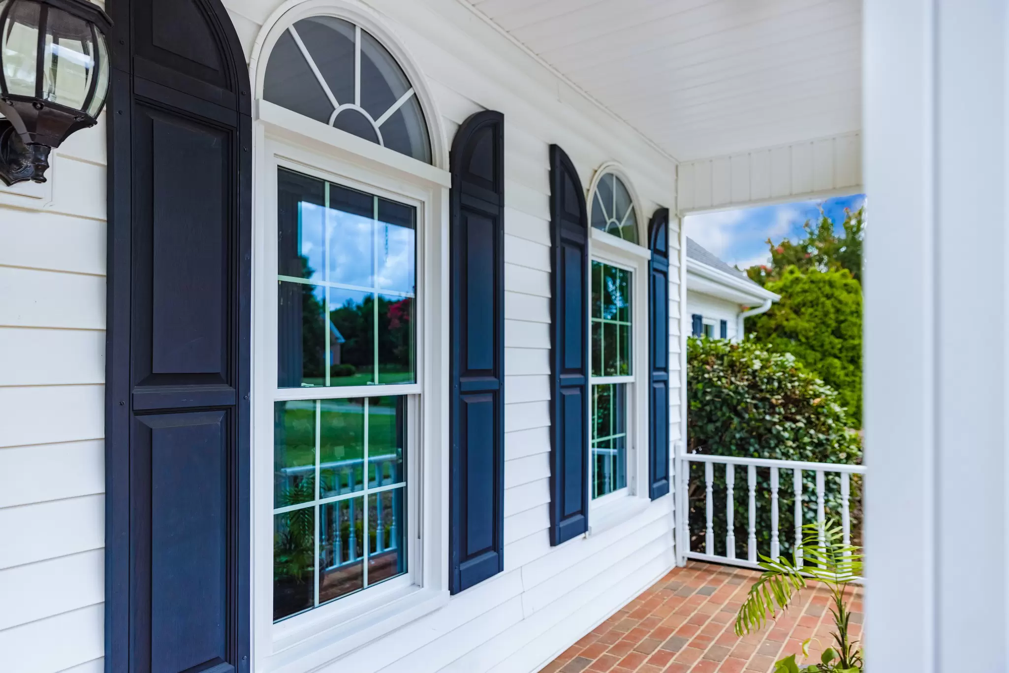 Front porch with white replacement windows and black shutters.