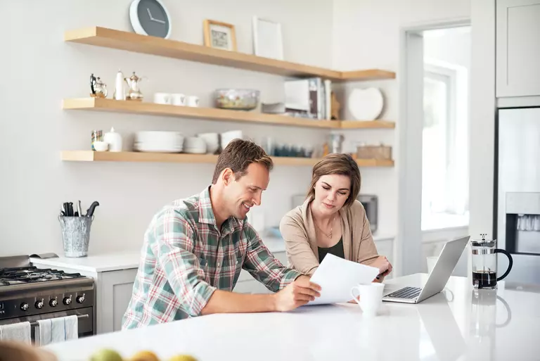 Man and woman sitting in the kitchen of home discussing how to finance home improvements.