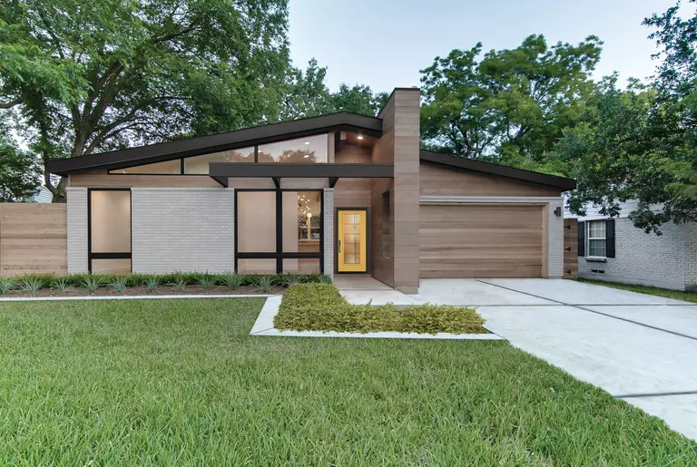 The front of a modern home with full-wall windows and neutral-tone colors.