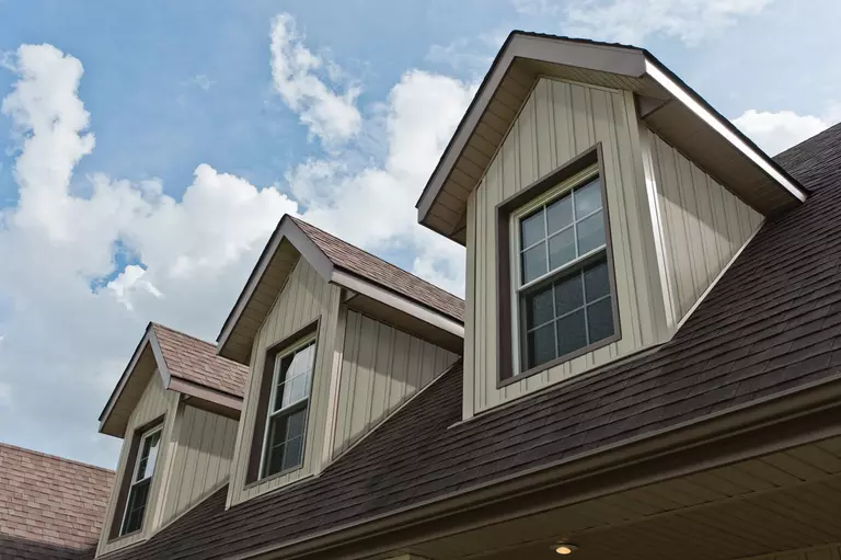 Upper level of a siding home, showing three dormers with energy-efficient windows over the roof of the home.