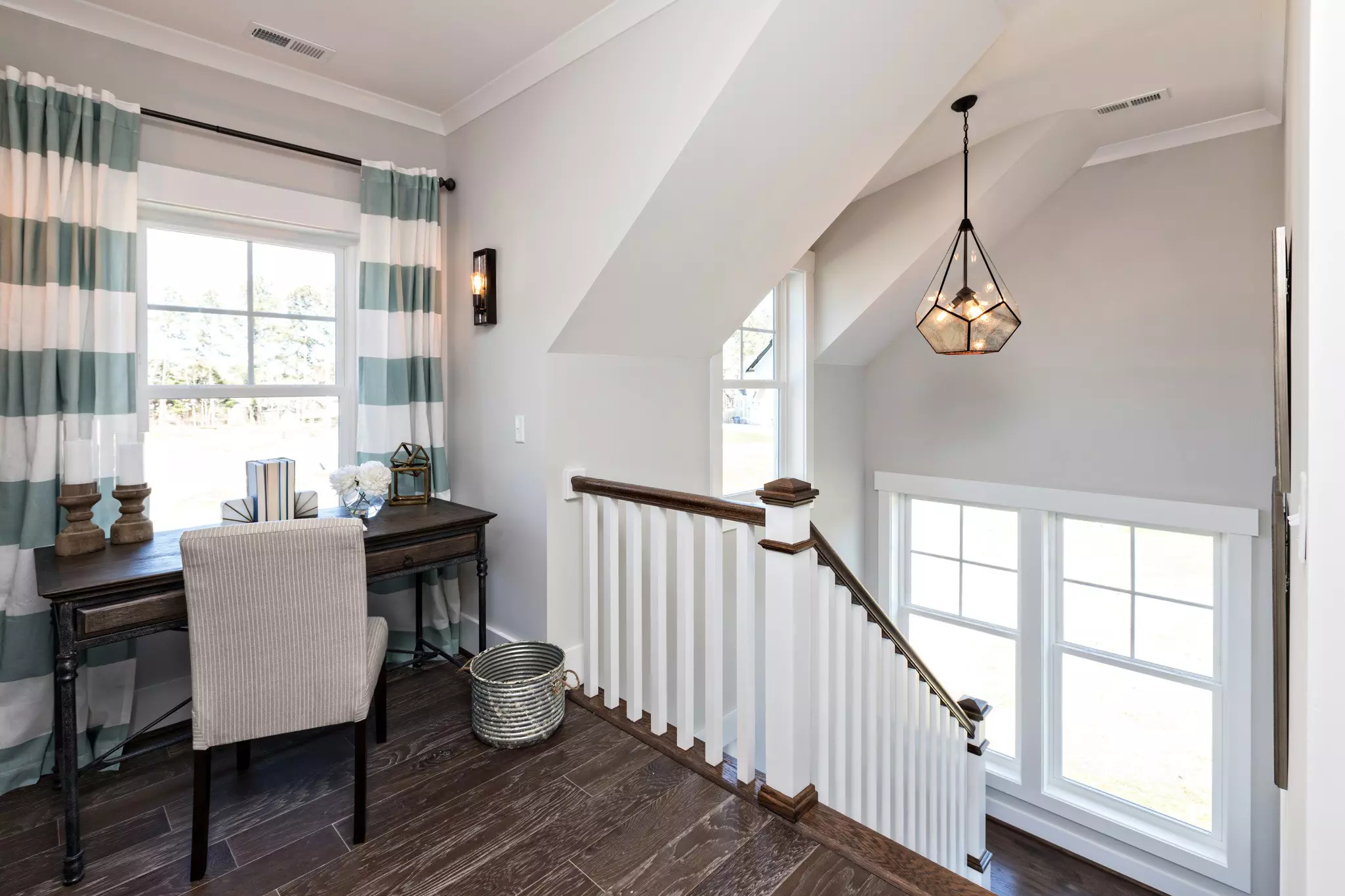 Upstairs home office with two tall windows letting in natural light.