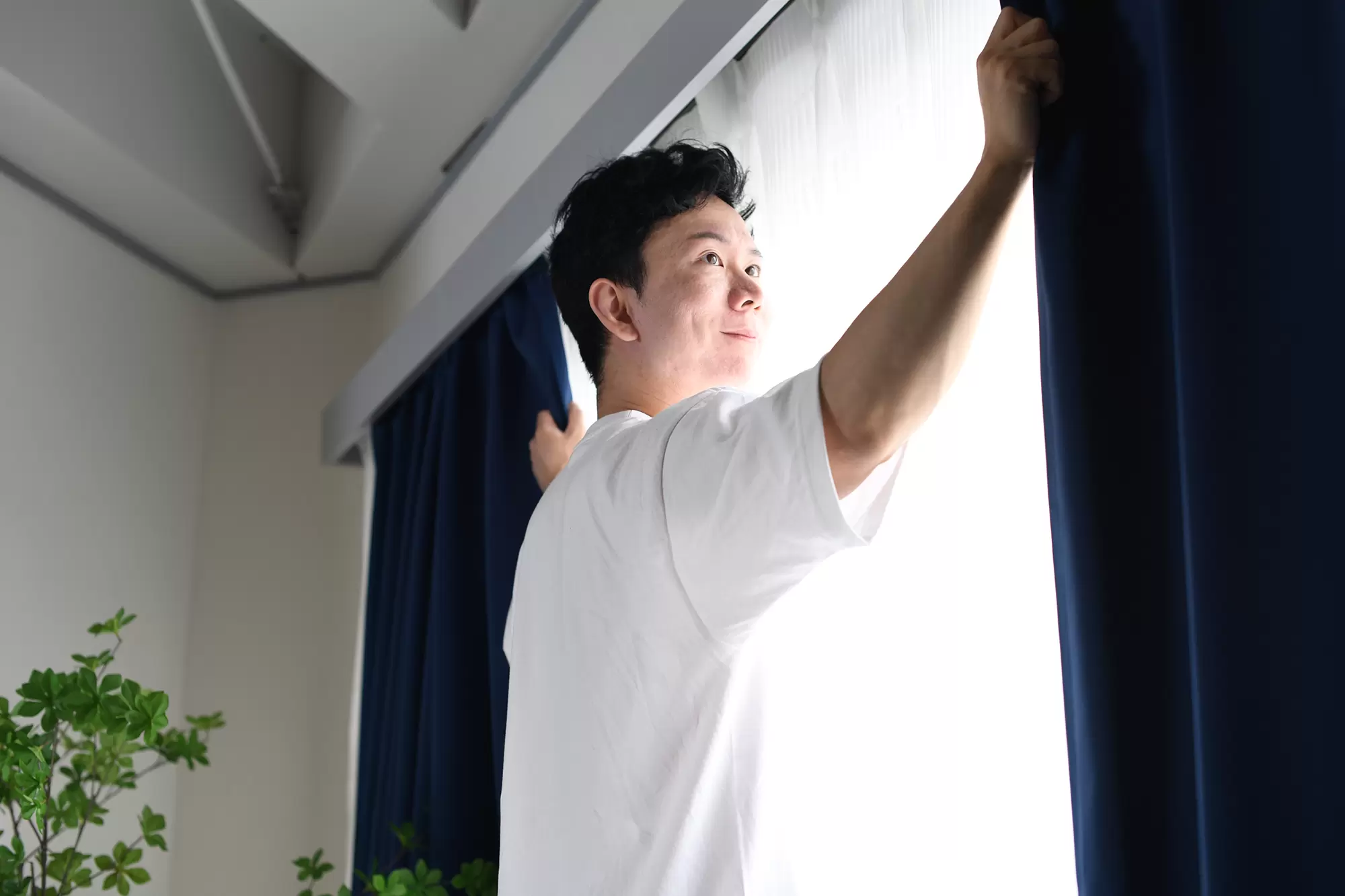 Man opening a set of curtains on a window.