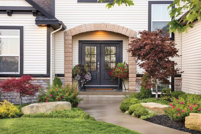 The front of a home with a luxury stone arch and dark double entry doors.