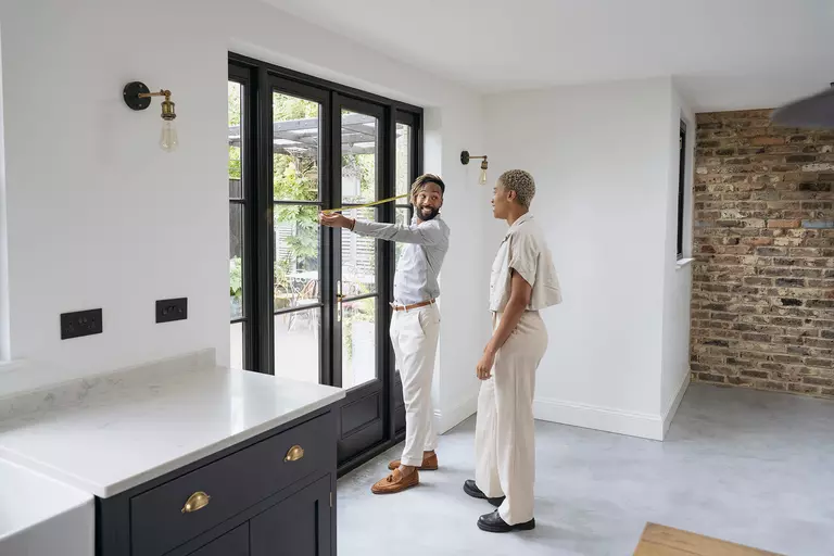Prospective buyers taking measurements of the home patio door in a luxury home.