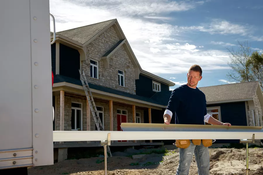 Contractor holding multiple slabs of wood to renovate a house.