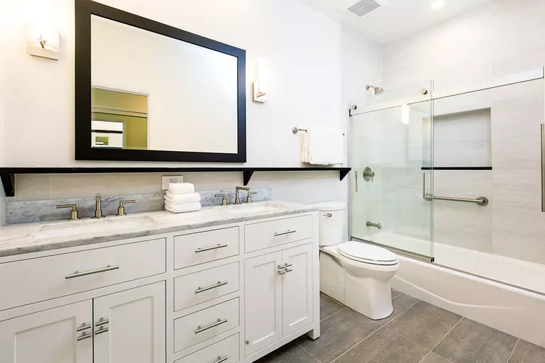 Bathroom interior with vanity, cabinets, mirror, toilet, and shower shown.