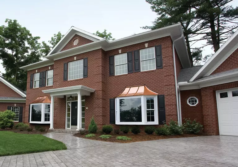Brick house with bay and double-hung windows and an attached garage door.