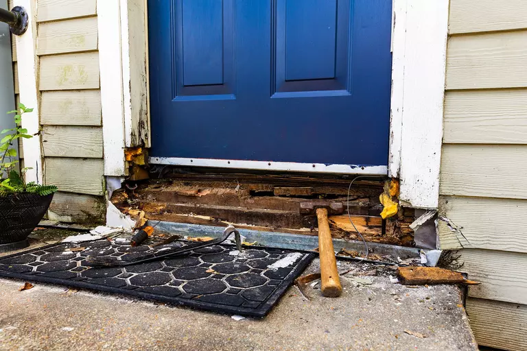 The bottom of an exterior door frame with moisture damage being removed.