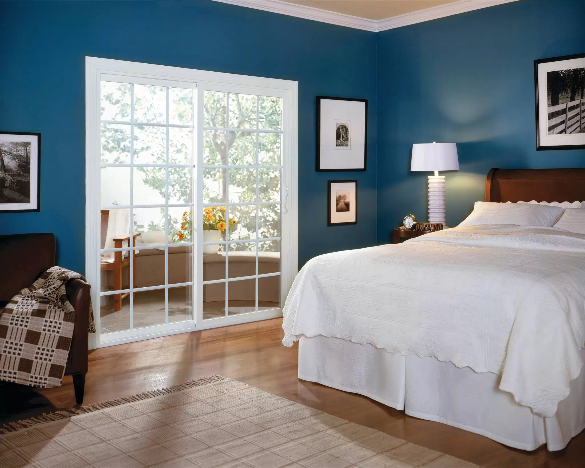 White sliding patio door with grids in a blue bedroom, letting daylight into the room.
