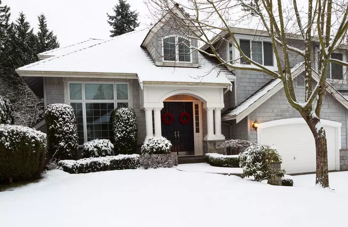 Snow-covered home with fiberglass entry doors with red Christmas wreaths attached