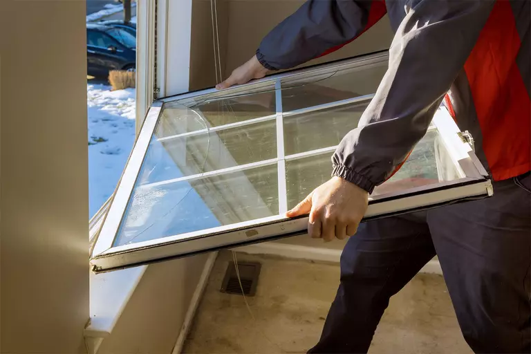 A man replacing a window in a home.