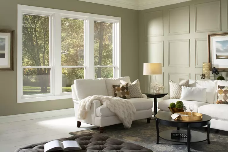 Sunlit furnished living room with three similar operable windows.