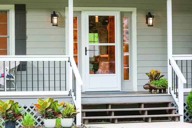 Front porch steps and a white storm door over a front door with two sidelites.