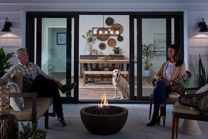 Sliding glass doors looking out on a couple sitting around a fire pit on the patio
