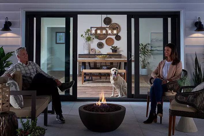 Sliding glass doors looking out on a couple sitting around a fire pit on the patio