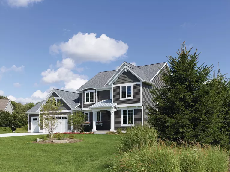 Front lawn of a two-story home with dark gray vinyl siding.