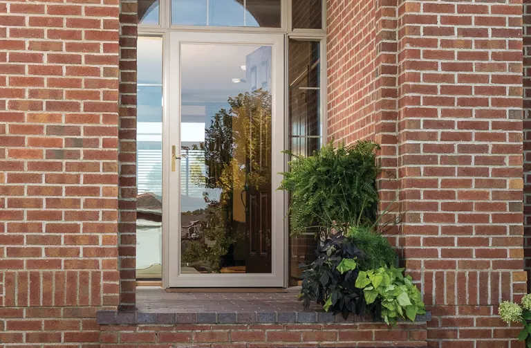Brick home exterior with a full view glass storm door.