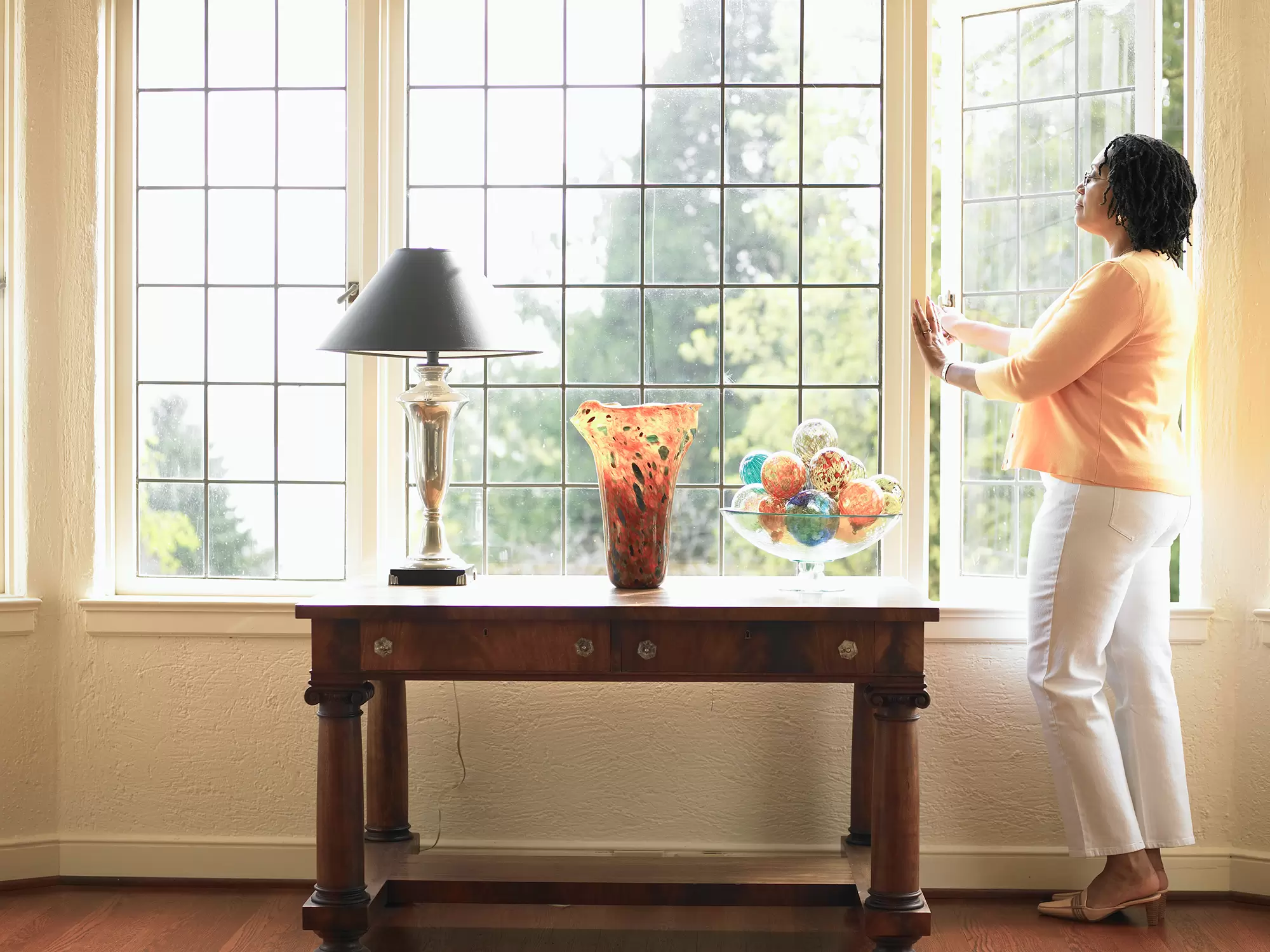 Woman opening a large casement window with grids.