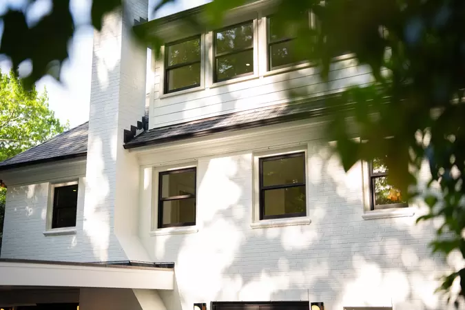 White brick home with black wood-clad double-hung windows