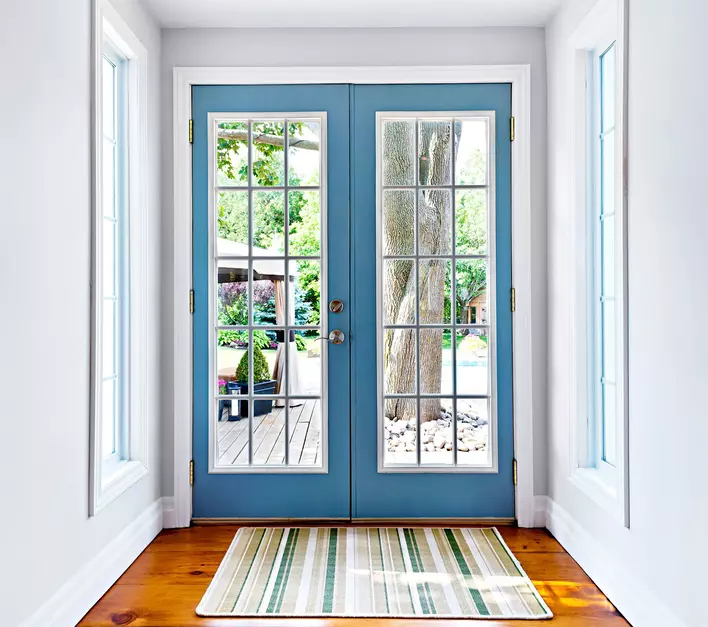 Light blue French patio door with a doormat in front of it.