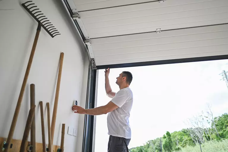 Man inspecting the underside of an open garage door.