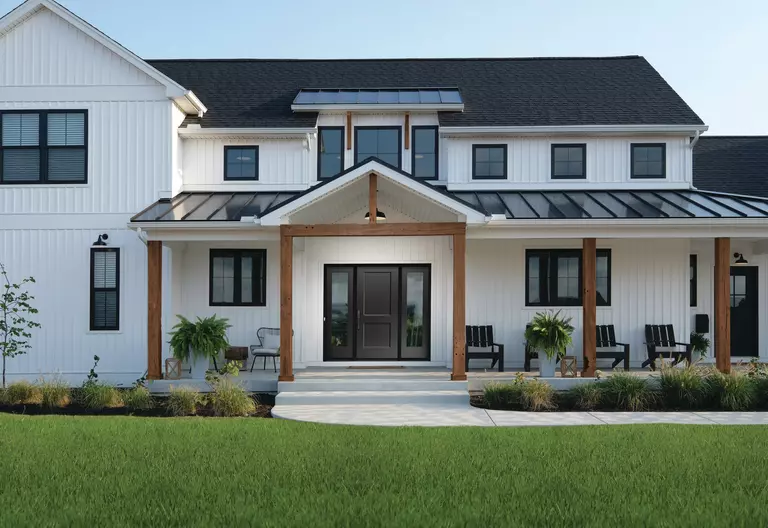 A modern home with black windows, white siding, and wood columns.