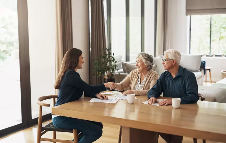 A woman having a meeting with an older couple with paperwork on the table.