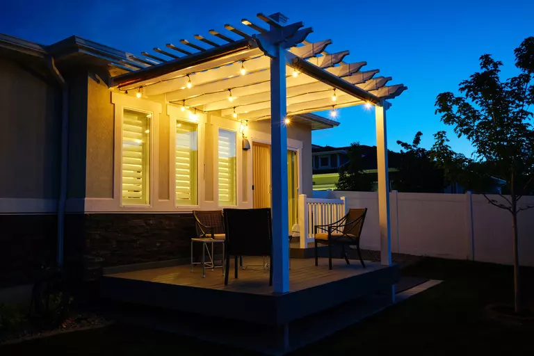 A pergola over a back patio that is decorated with string lights to create a cozy atmosphere.