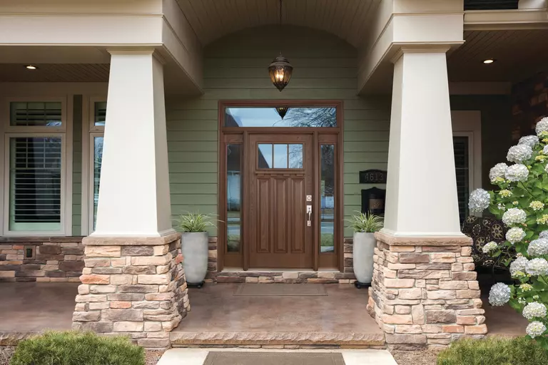 A dark brown front door with a pair of glass sidelites and transom.